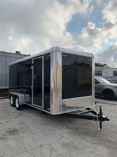 Black enclosed cargo trailer parked on a lot with a car in the background