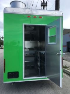 Green industrial trailer with an open door, showing metal equipment inside.