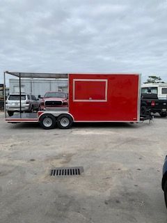 Red enclosed utility trailer parked in a lot, with a white-framed window and open side storage area.