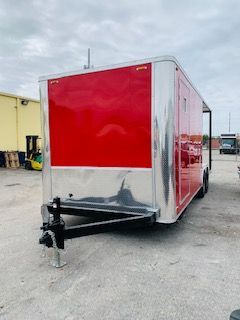 Red cargo trailer with silver trim parked in an industrial lot.