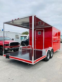 Red enclosed trailer with open front ramp and reflective floor in a parking lot
