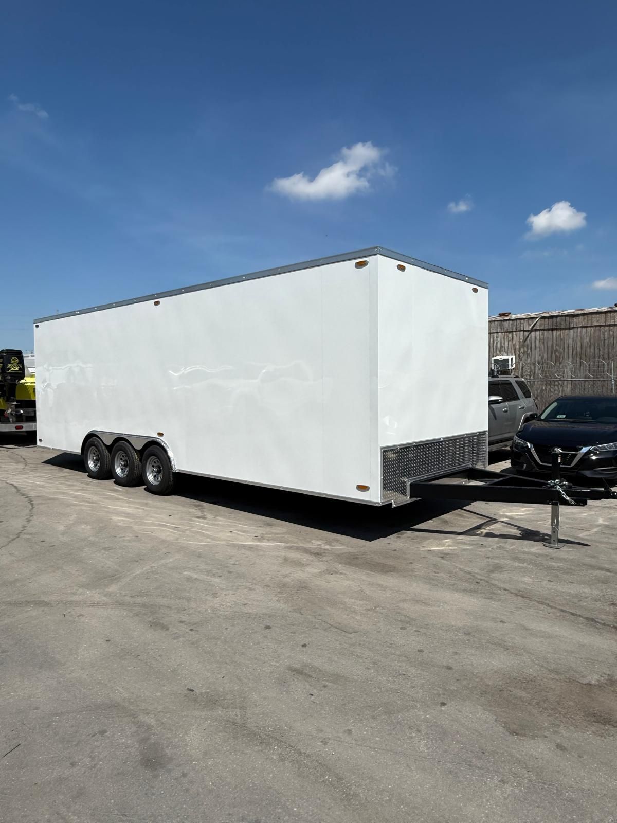 White enclosed cargo trailer parked on a lot under a blue sky