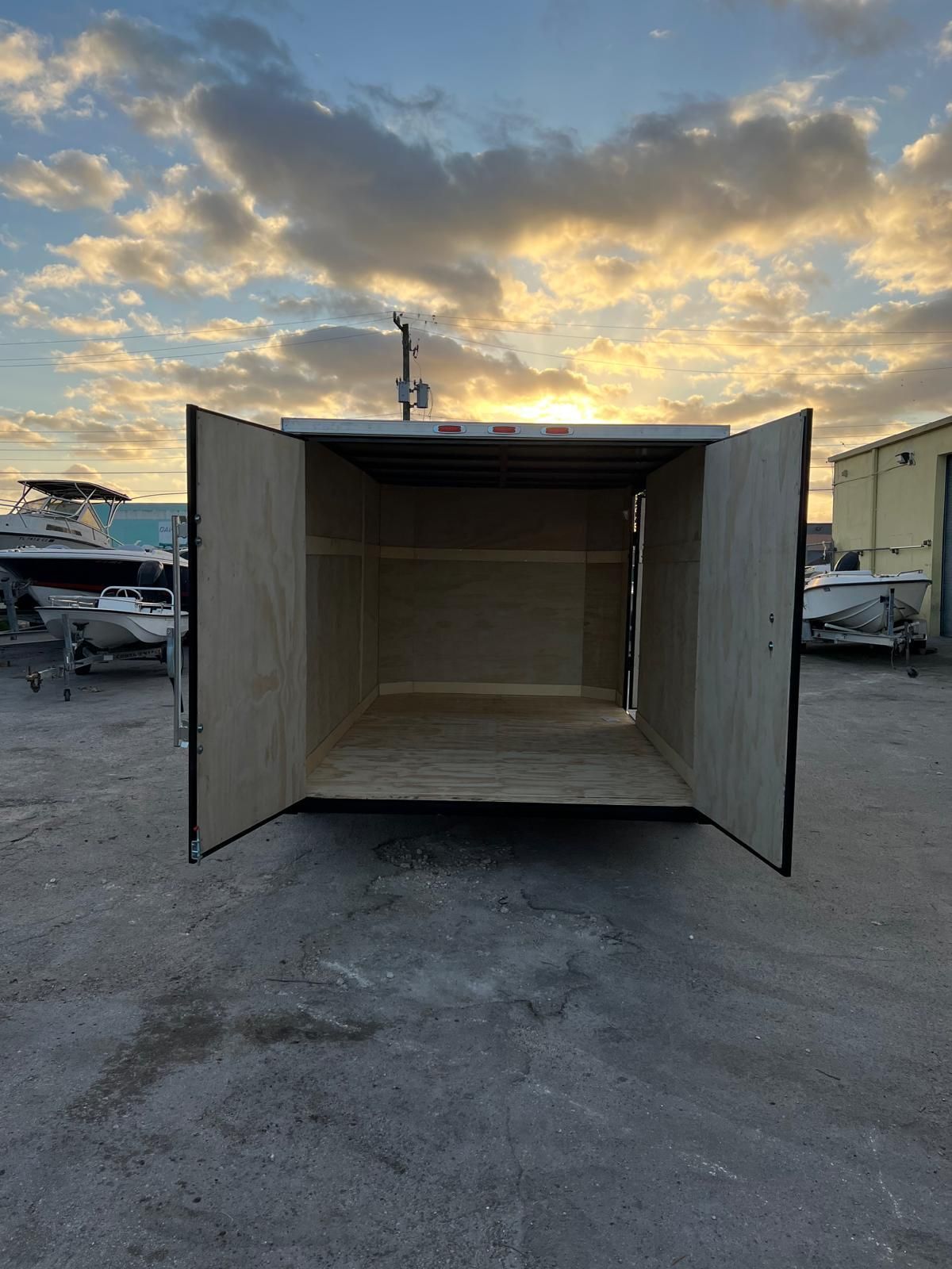 Open wooden shipping crate with both doors open in a marina parking lot at sunset
