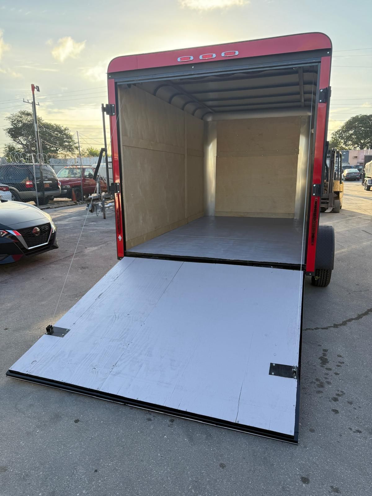 Open box truck with lowered ramp, showing empty cargo area in a parking lot.
