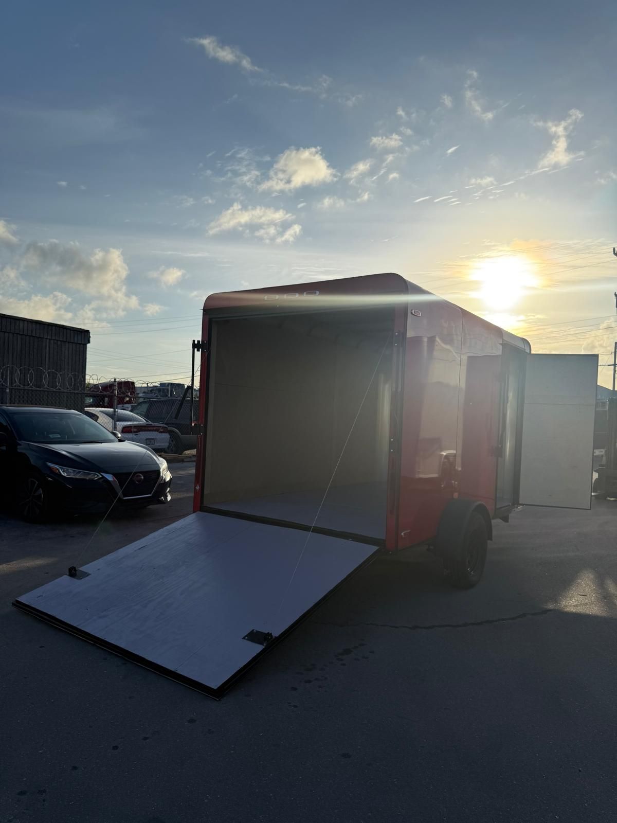 White box truck with rear ramp open in a parking lot at sunset