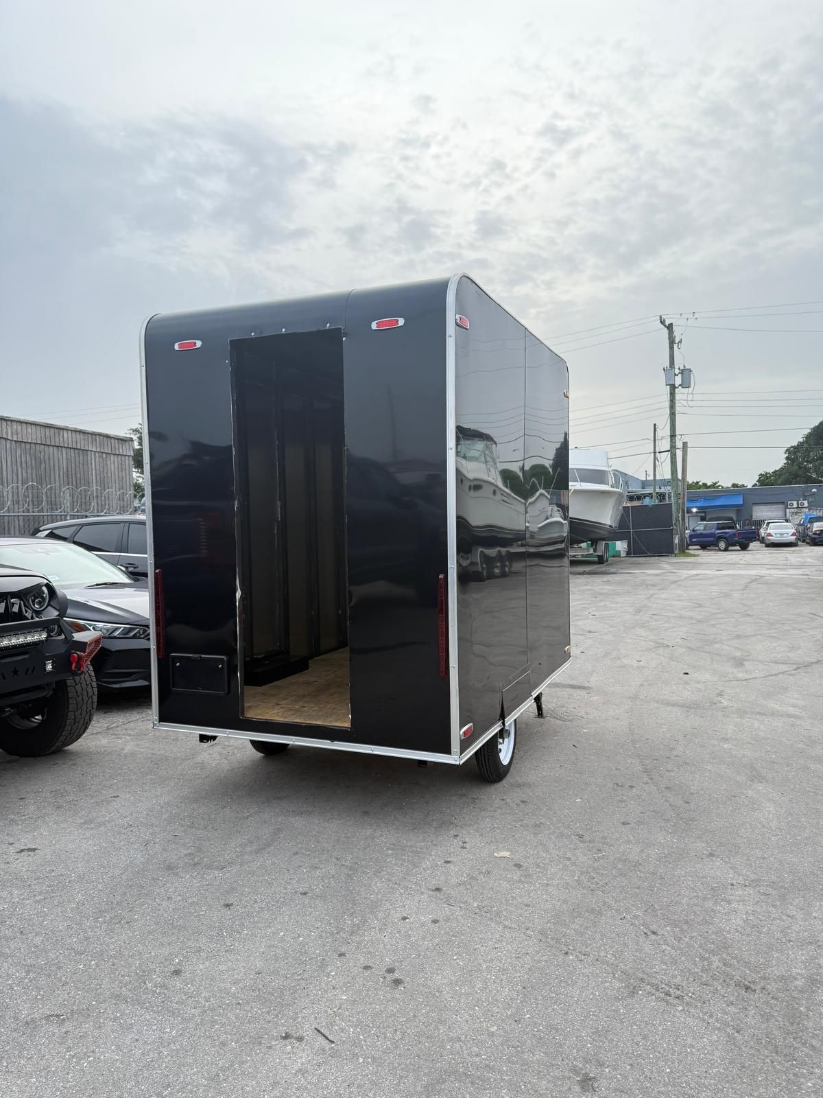 Black enclosed trailer parked in a lot with its rear door open.
