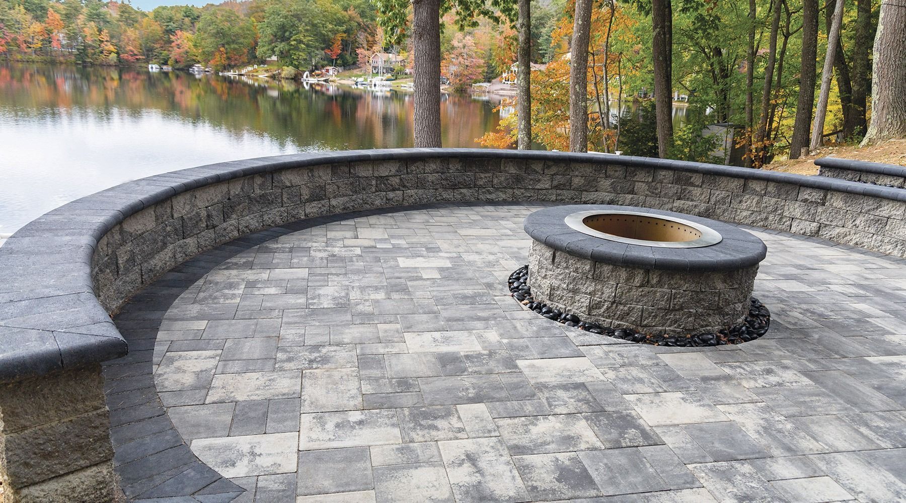 A fire pit is sitting on a patio next to a lake.