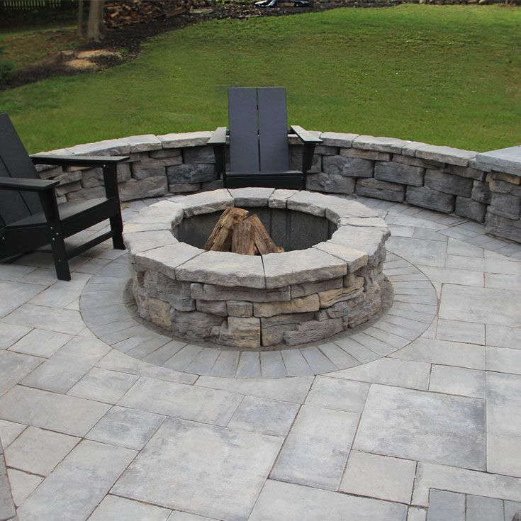 A fire pit on a patio with chairs around it