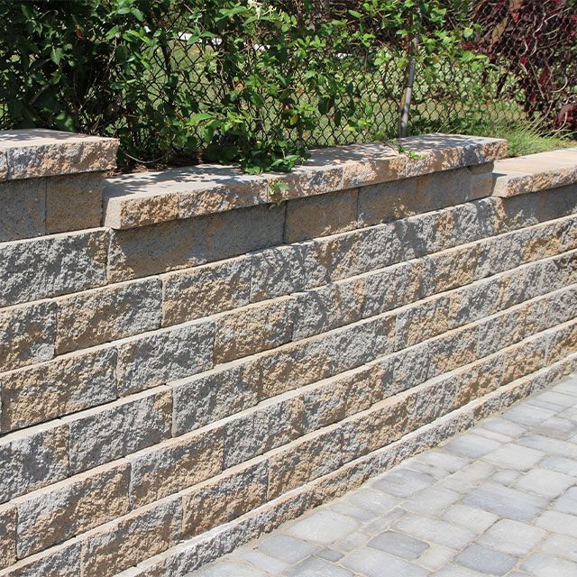 A stone wall with a brick walkway in front of it