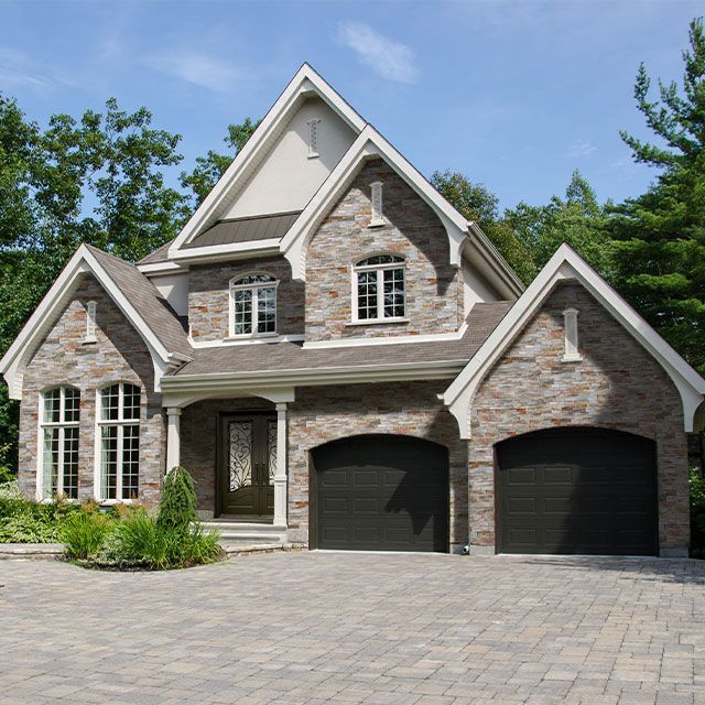 A large brick house with two black garage doors