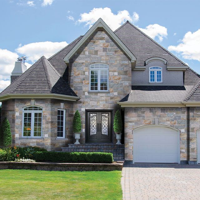 A large stone house with a white garage door