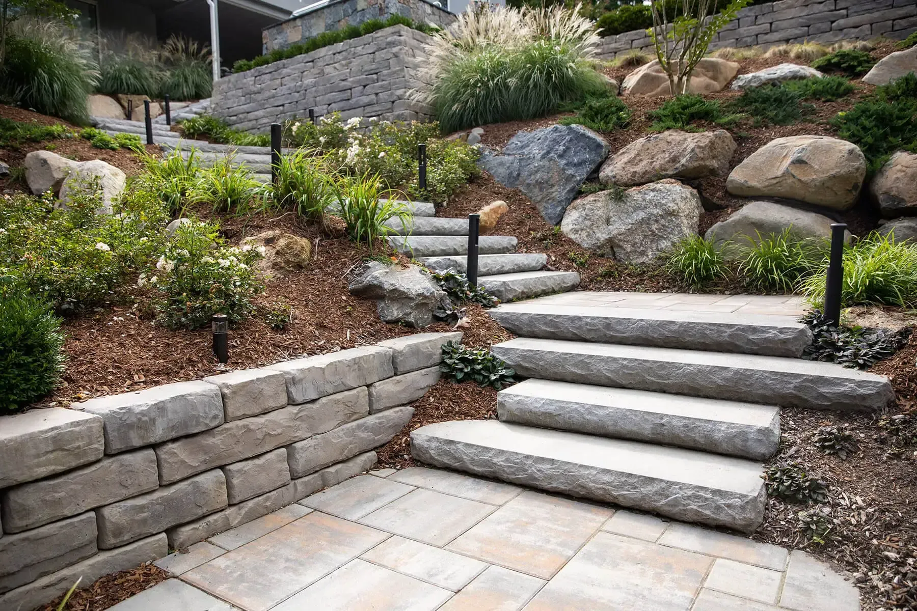 A set of stairs leading up to a stone wall in a garden.