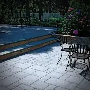 A patio with a table and chairs next to a pool.