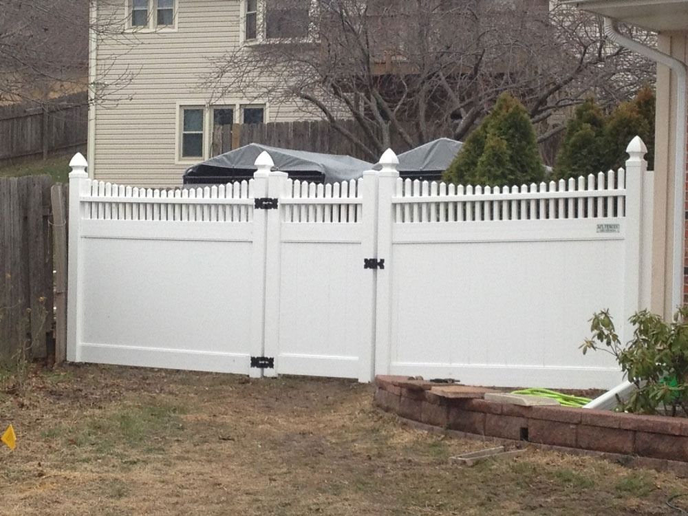 White vinyl fence with gate in front of a house.