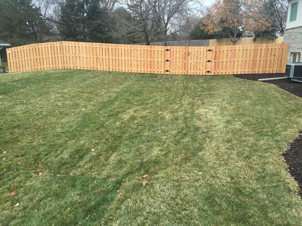 Wooden fence in a grassy yard, with a slightly sloped lawn.