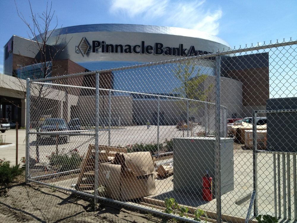 Pinnacle Bank Arena is behind a chain-link fence, with construction materials in the foreground.
