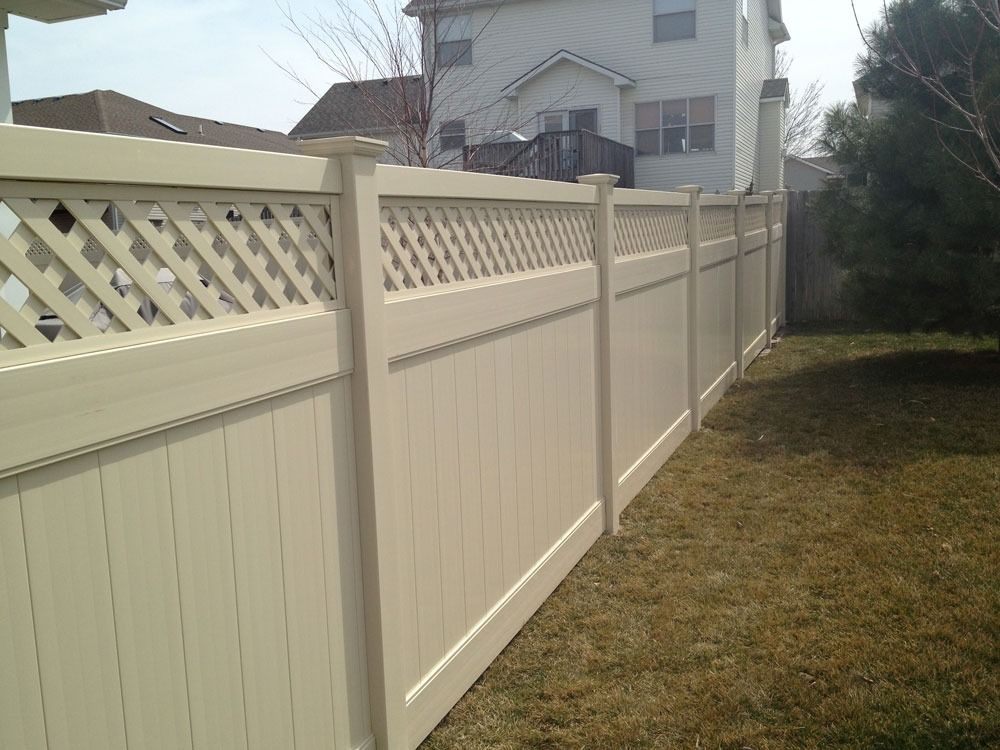 Beige vinyl fence with lattice top in a backyard setting.