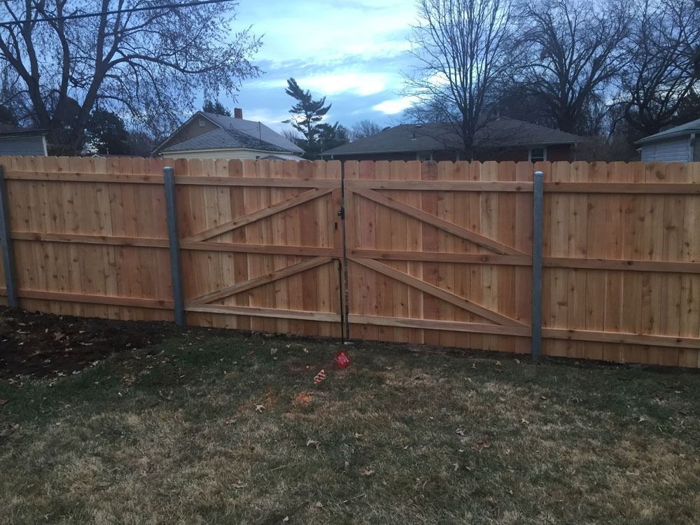 Wooden fence with gate in backyard. Gate has diagonal bracing.