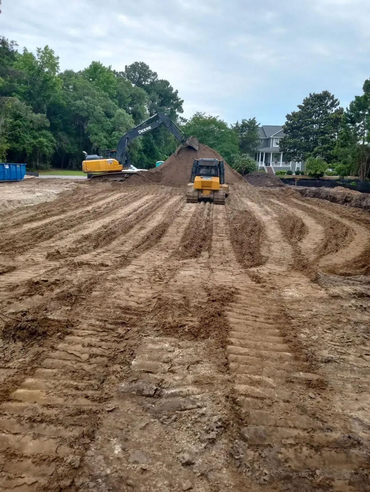 Construction site with two yellow earthmovers working on brown soil.