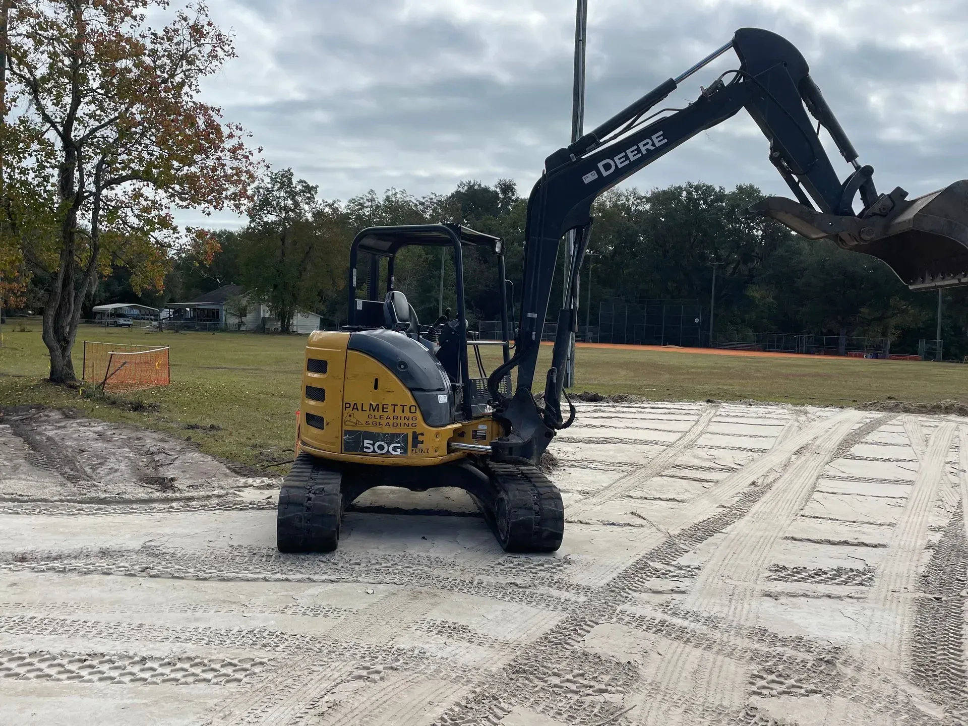 Yellow excavator scoops dirt from sandy ground.