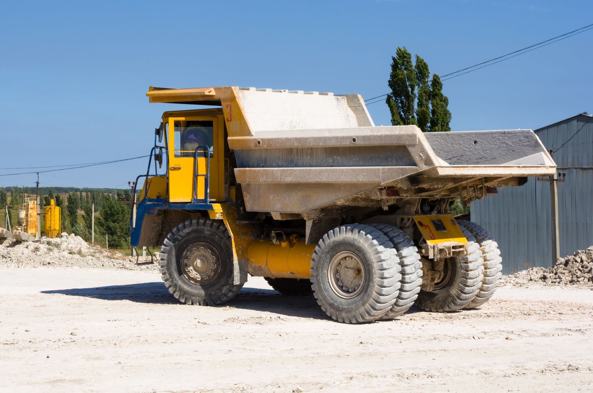 Yellow dump truck hauling material on a construction site.