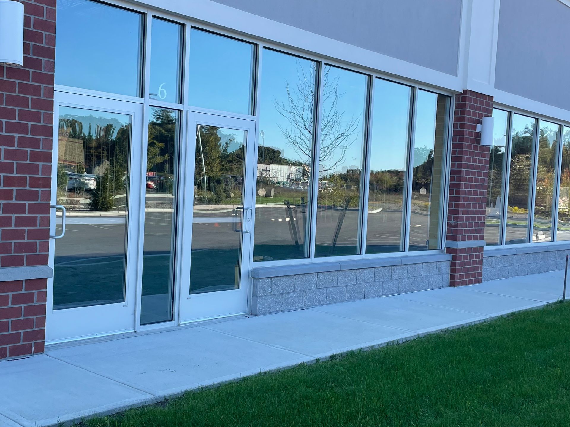 Exterior of a commercial building with large windows reflecting the sky and surroundings. Brick and stone facade.