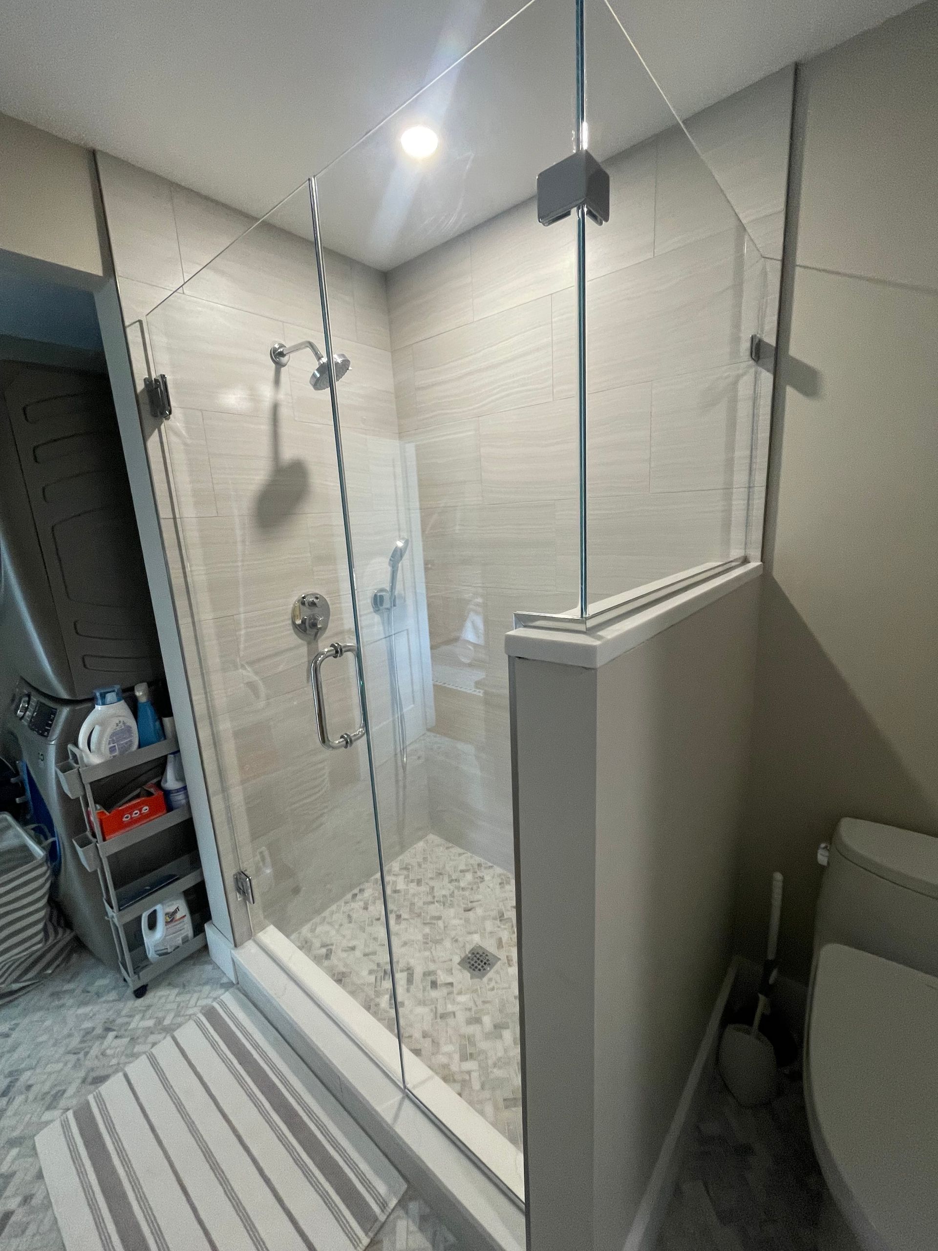 Shower with clear glass doors, tiled walls and floor, and chrome fixtures.