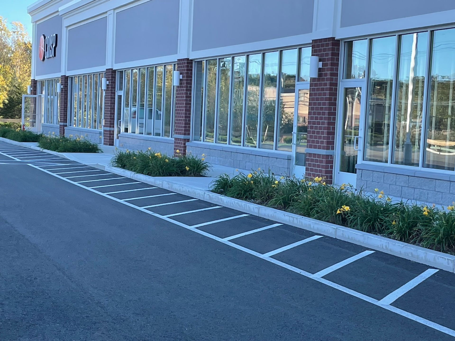 Exterior of a store with large windows, brick columns, and a marked accessible parking area.