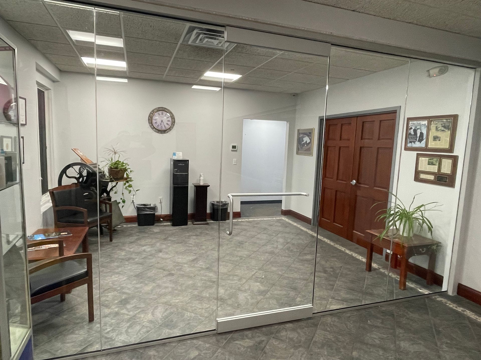 Interior office space with mirrored walls, plants, and wooden doors.
