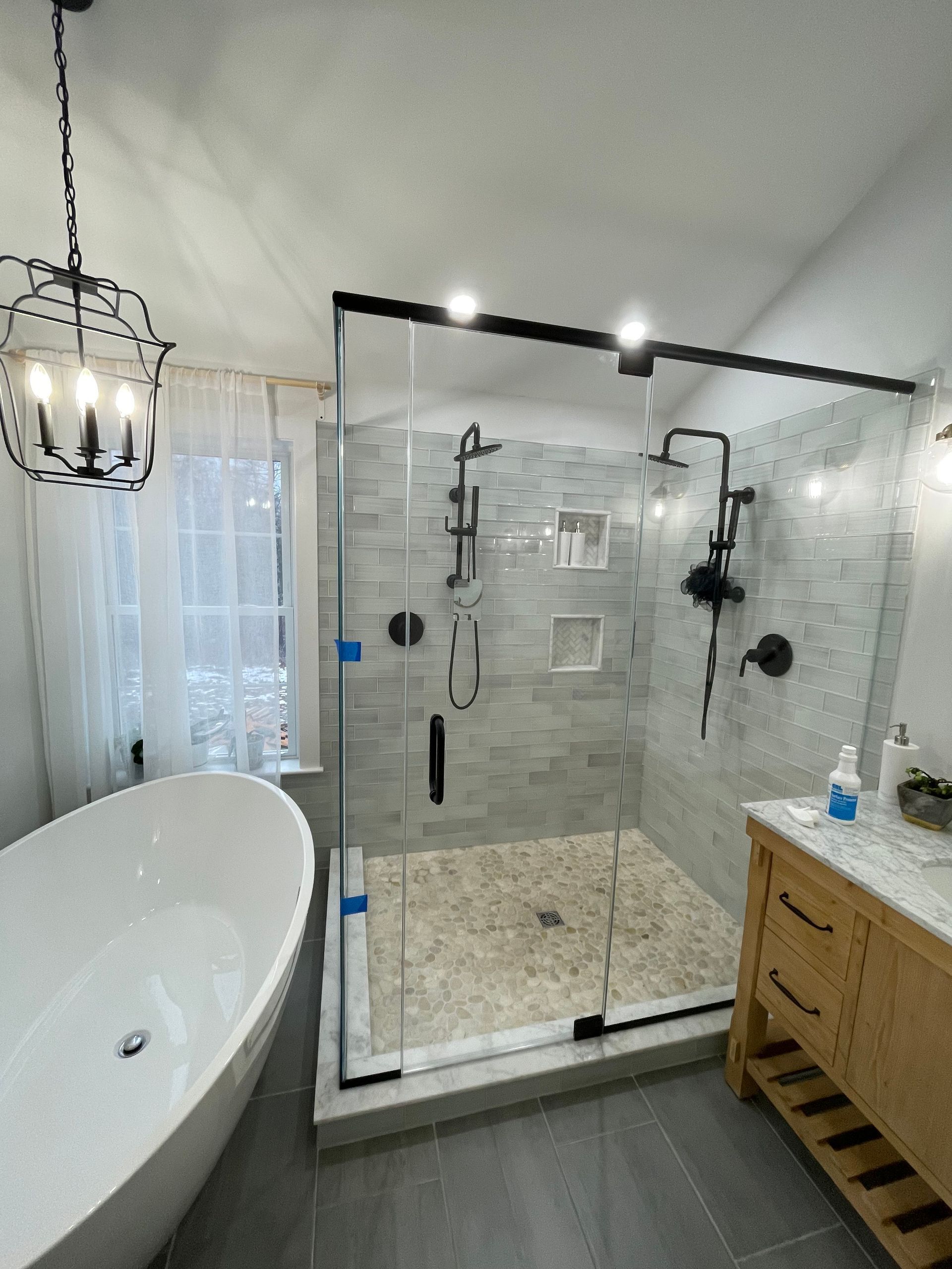 Bathroom with a white soaking tub, glass shower, and wooden vanity.