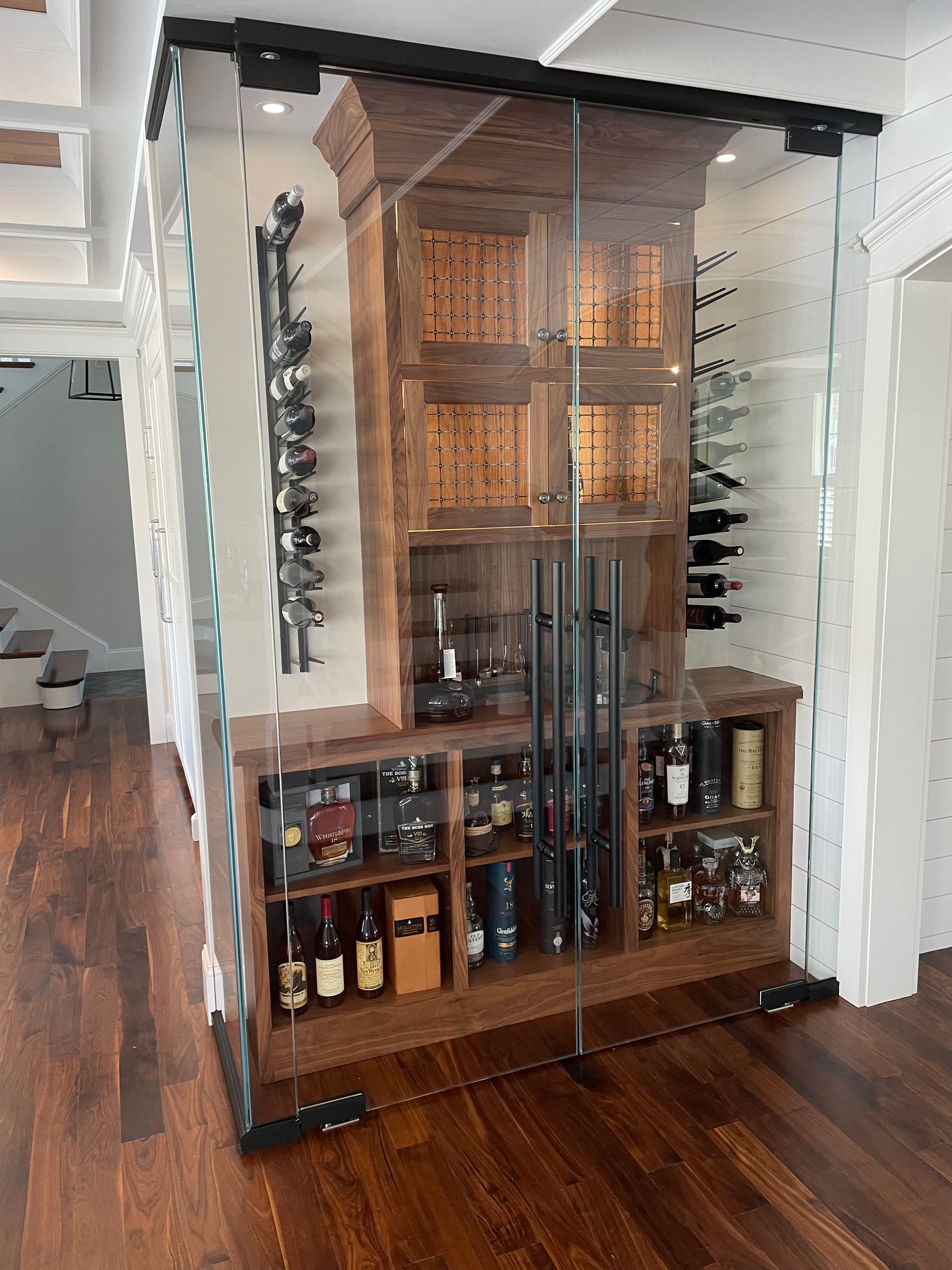Wine cabinet encased in glass, showcasing bottles, wooden shelves, and wine racks.