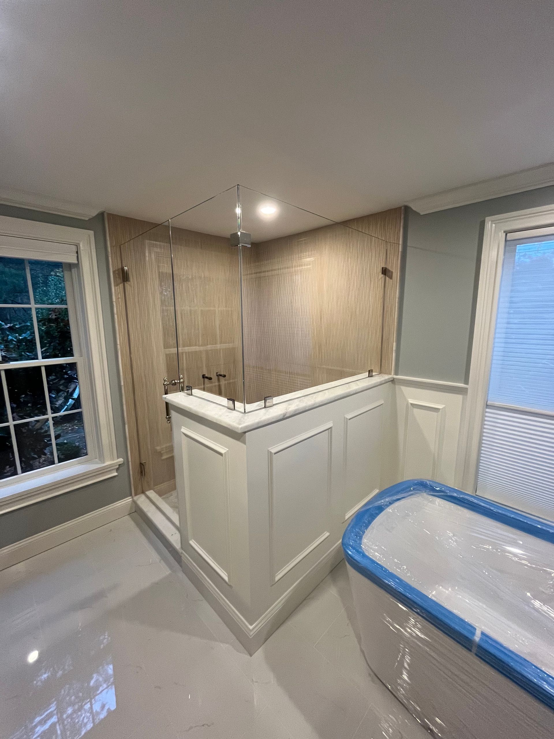 Bathroom remodel with a glass shower, white paneling, and a wrapped bathtub.