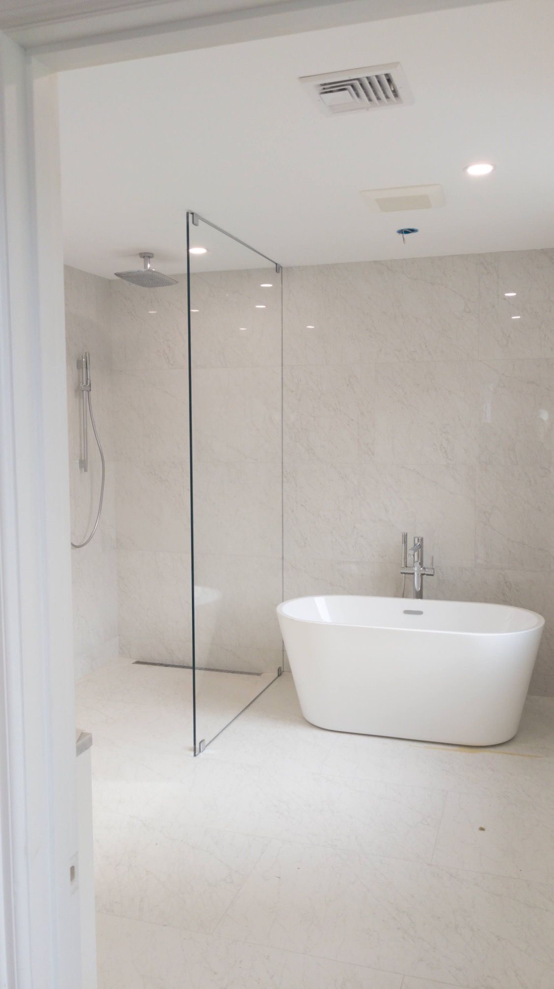 Modern bathroom with a glass shower, soaking tub, and neutral-colored tile.