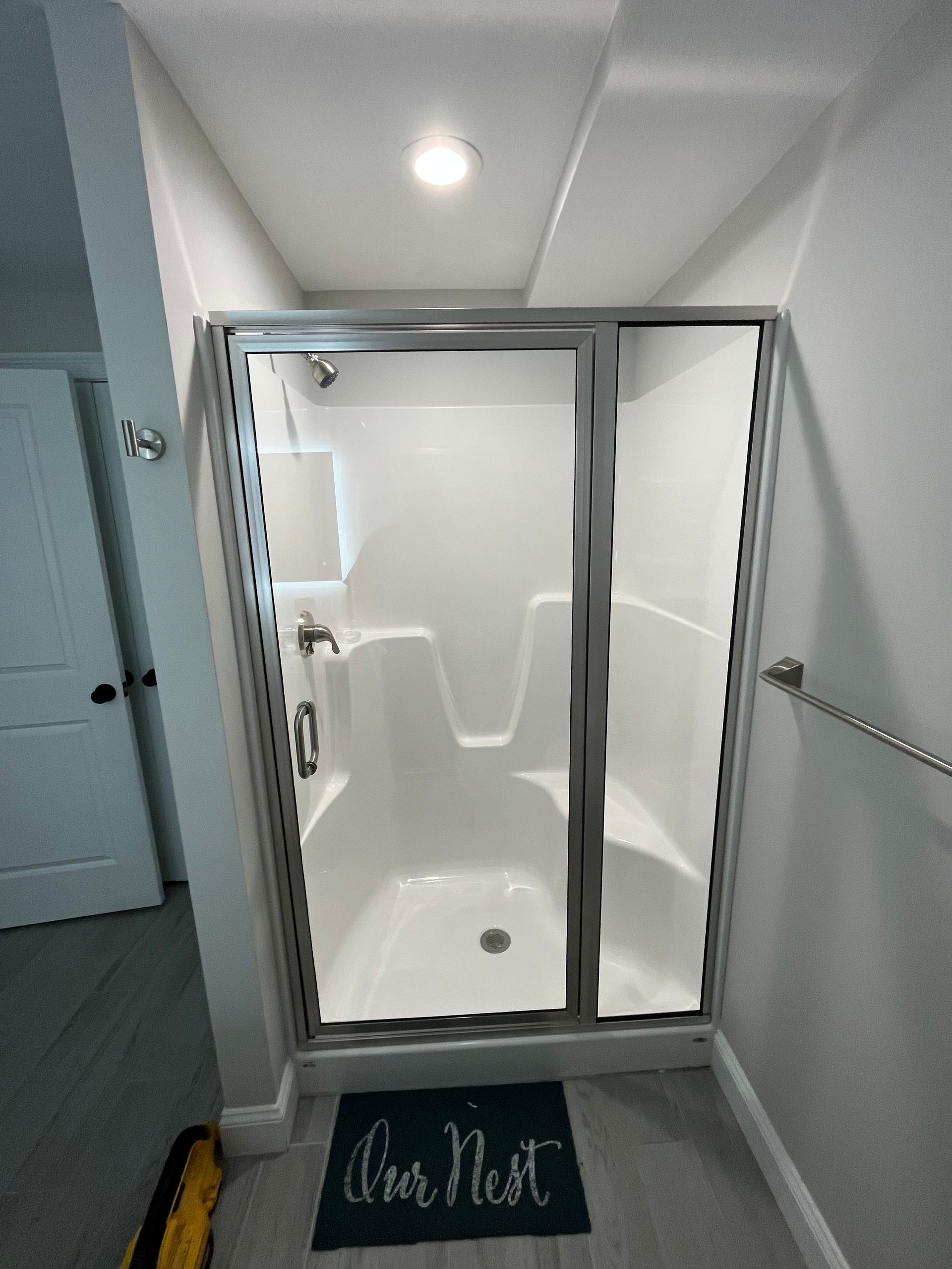 A white shower stall with glass doors, silver hardware, and a 