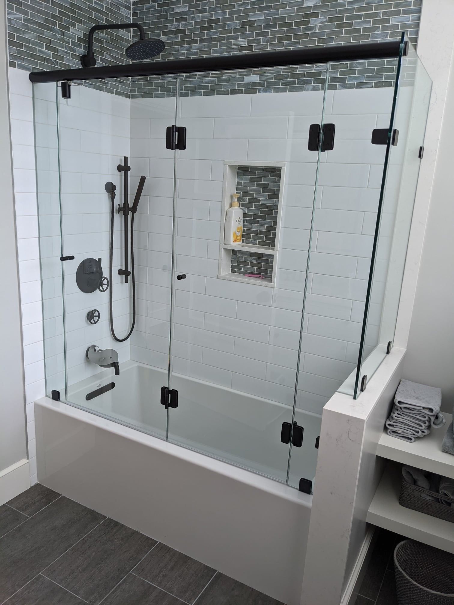 Modern bathroom with a glass shower enclosure and black fixtures.