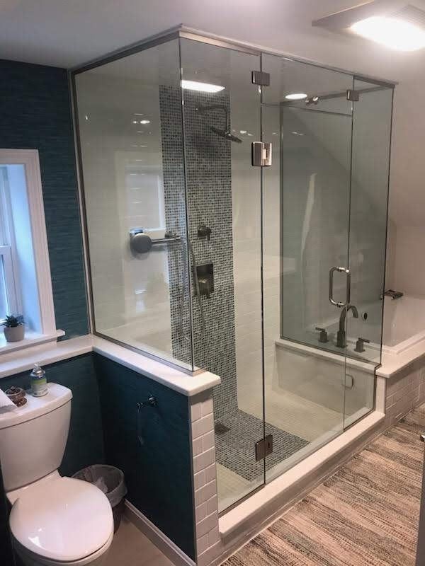 Modern bathroom with glass shower enclosure, mosaic tile accent wall, toilet.