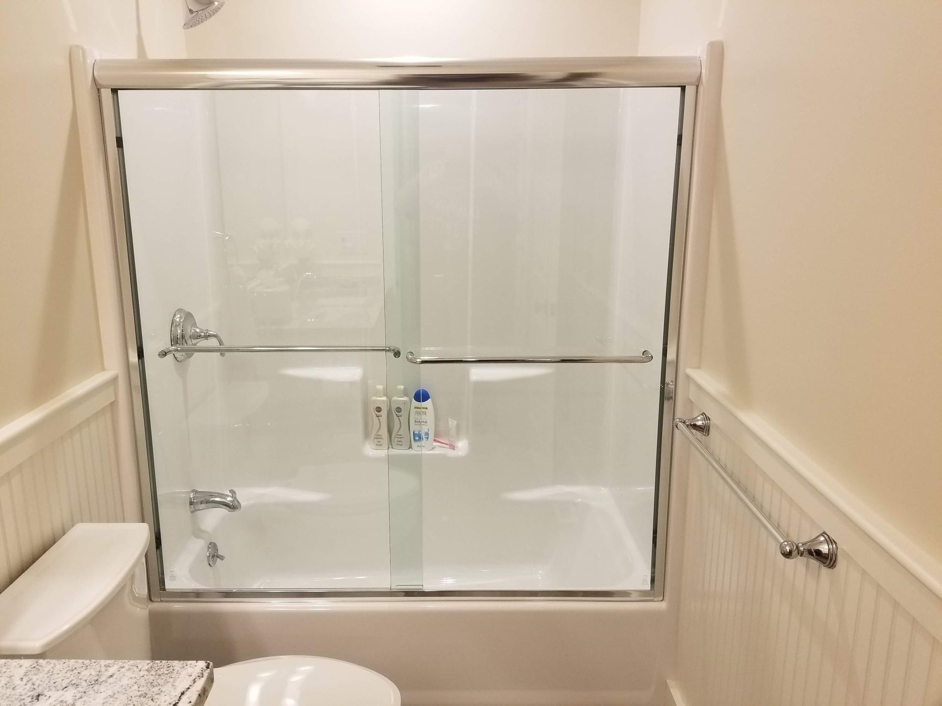 White bathroom with sliding glass shower door and a toilet.