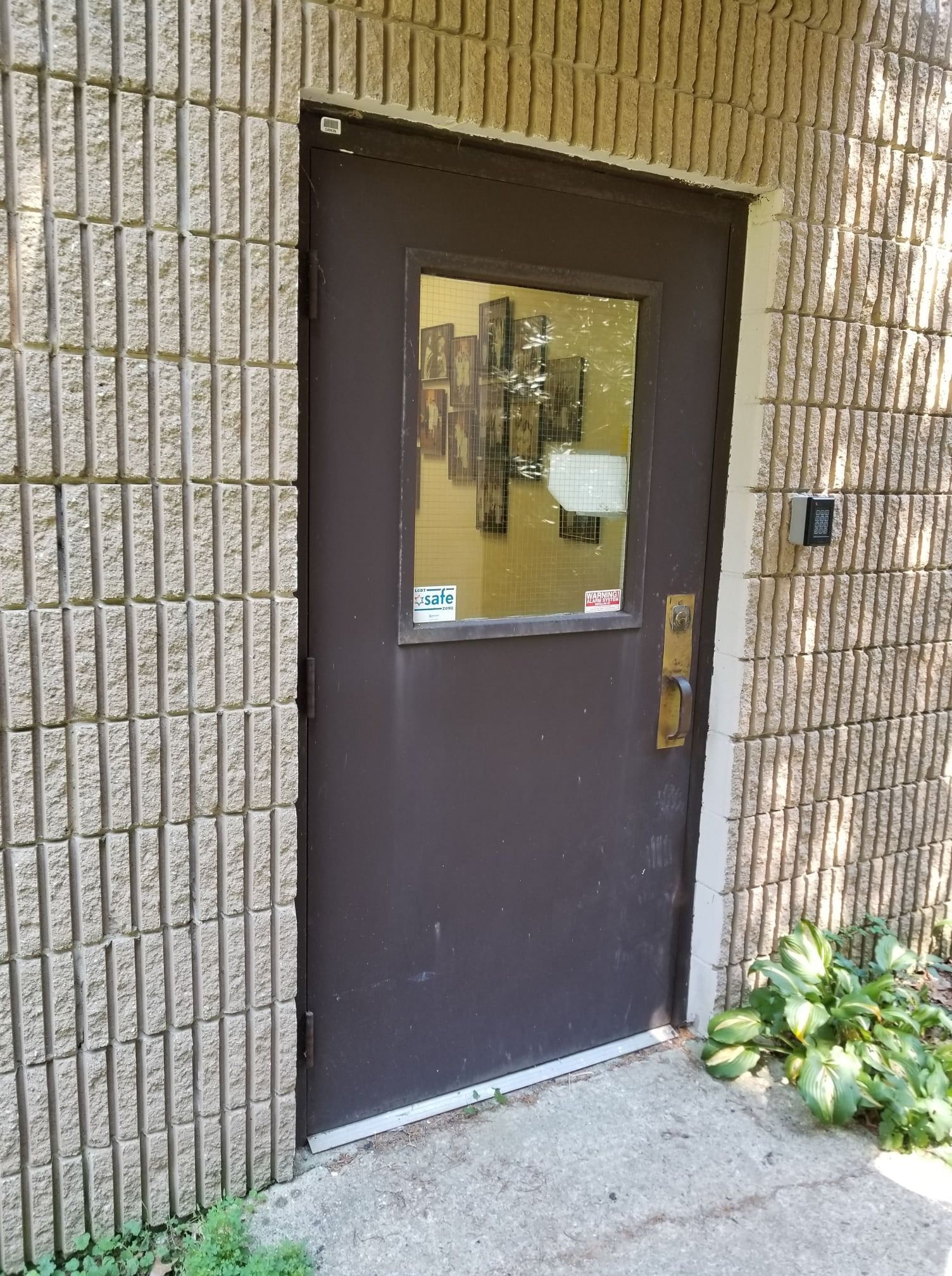 Brown door with glass window, set in a textured brick wall.