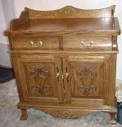 A wooden cabinet with drawers and doors is sitting on a carpet in a room.