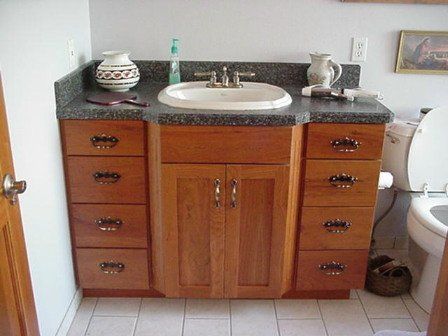 A bathroom with a sink, toilet, and wooden cabinets.
