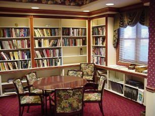 A room with a table and chairs in front of a bookshelf filled with books.