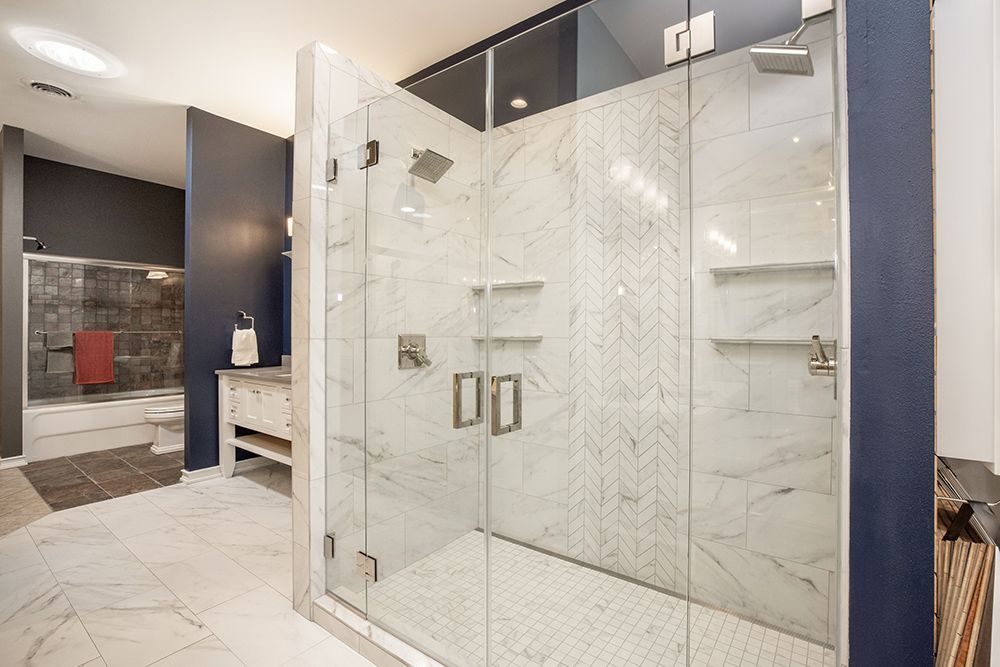 A bathroom with a walk in shower with a glass door.