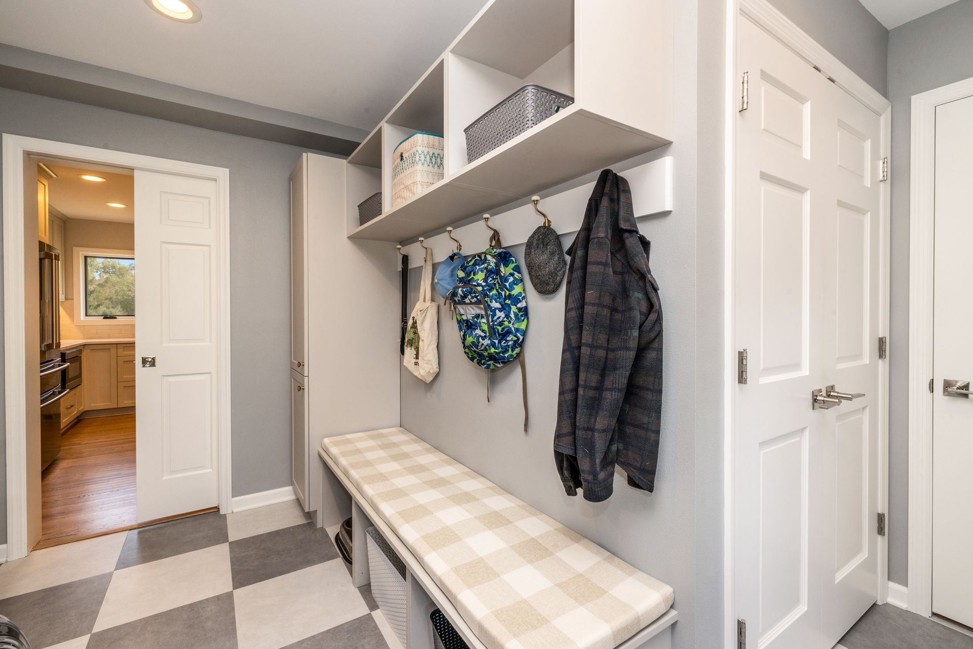 There is a bench in the middle of the room with clothes hanging on the wall.