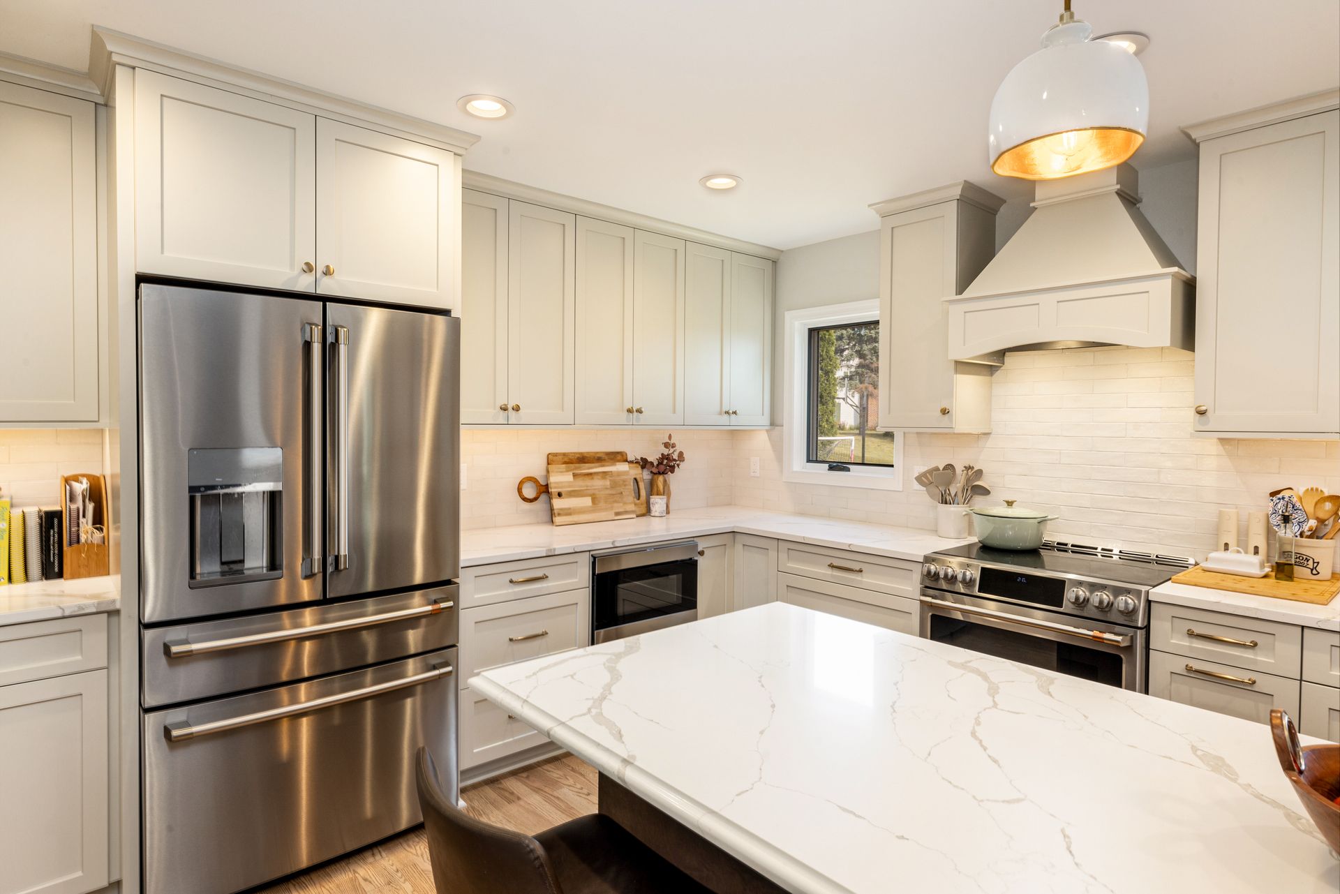 A kitchen with white cabinets, stainless steel appliances, and a large island.