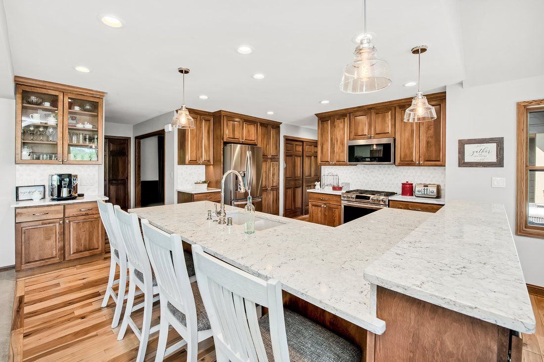 A kitchen with a large island and white counter tops.