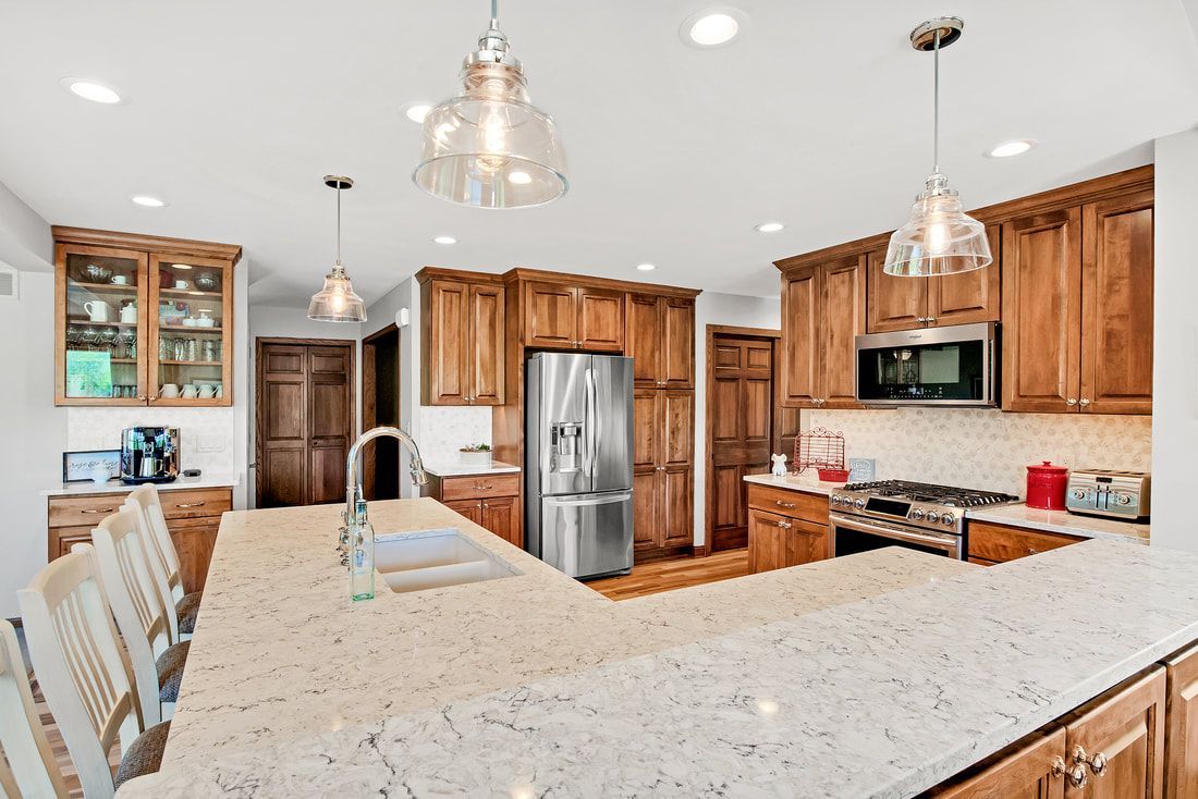 A kitchen with wooden cabinets , granite counter tops , stainless steel appliances and a large island.