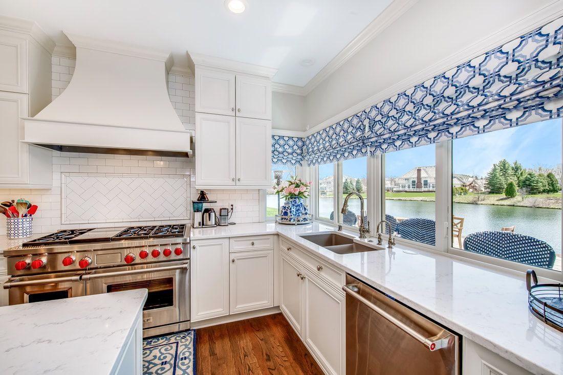 A kitchen with white cabinets , stainless steel appliances , a stove and a sink.