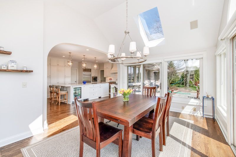 A dining room with a wooden table and chairs and a skylight.