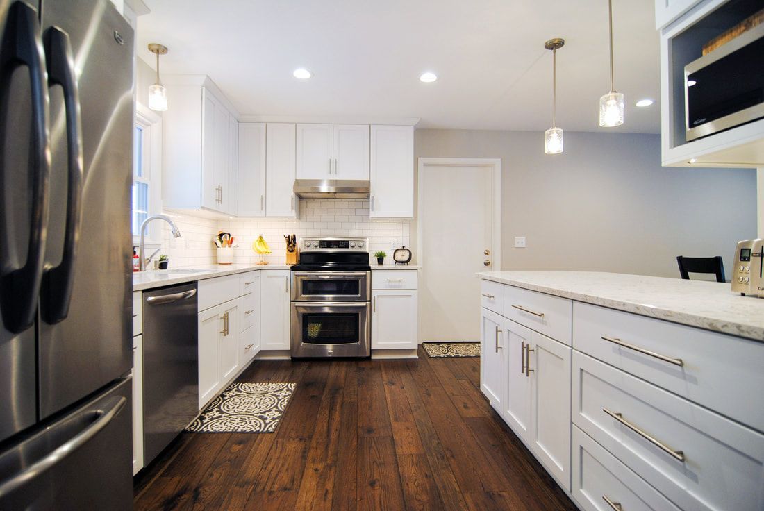 A kitchen with white cabinets , stainless steel appliances , and hardwood floors.