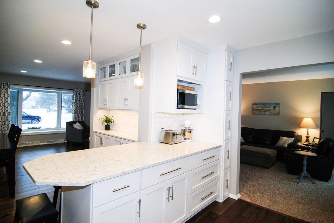 A kitchen with white cabinets and a large island in the middle of the room.